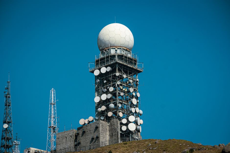 Imponente torre de satélite com várias antenas contra um vibrante céu azul.