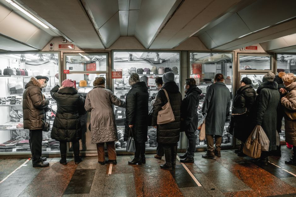 Adultos analisando roupas de inverno em um shopping interno durante o dia.