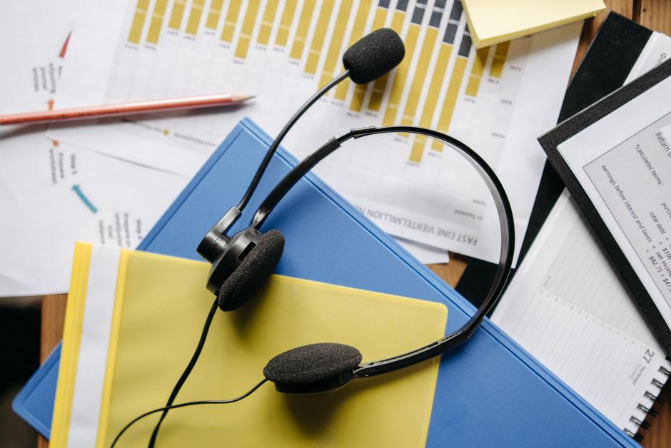 Close-up de uma mesa de escritório com headset, gráficos e documentos mostrando suporte ao cliente.