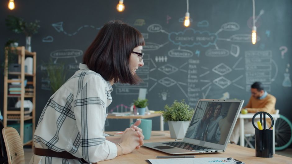 Mulher de negócios participando de uma videochamada em um escritório moderno com decoração criativa.