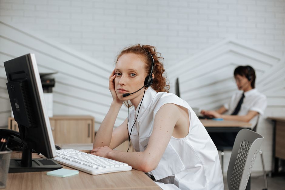 Agente de call center focado com fone de ouvido trabalhando em uma mesa de escritório moderna.