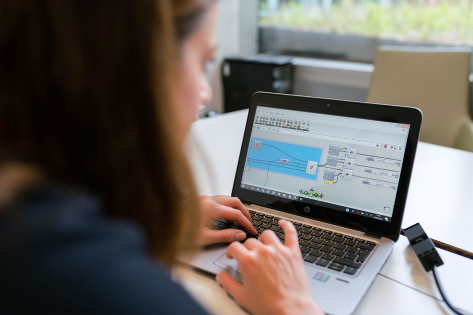 Uma engenheira se concentra na análise de software usando um laptop em ambientes internos.