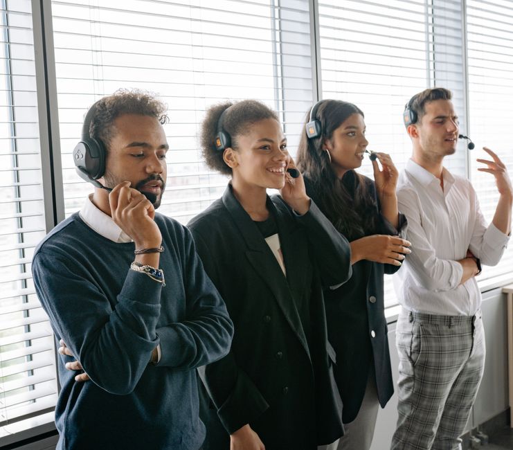 Equipe diversificada de call center colaborando em um escritório moderno, usando fones de ouvido e sorrindo.
