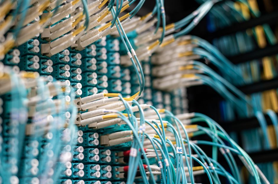 Vista detalhada de cabos de fibra óptica conectados a um painel de interconexão em um data center.